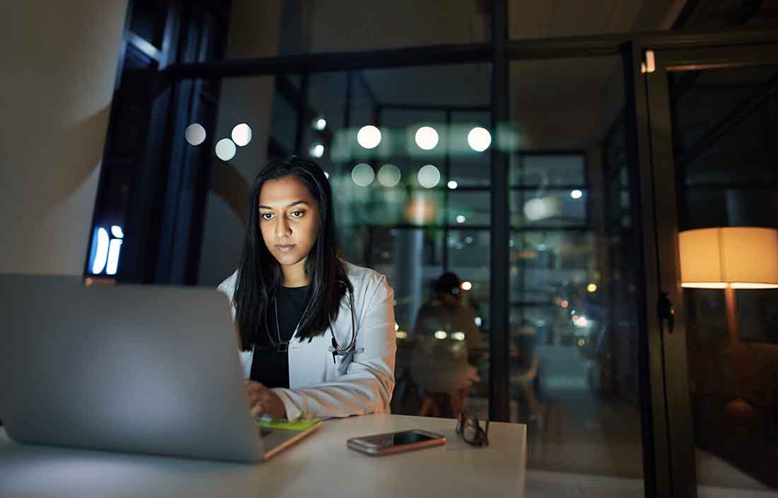 Doctor working on their laptop computer late at night.