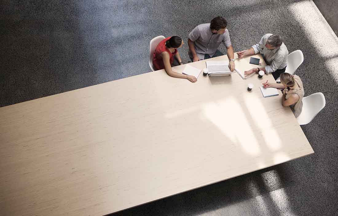A top down view of business professionals gathered around a conference room table.