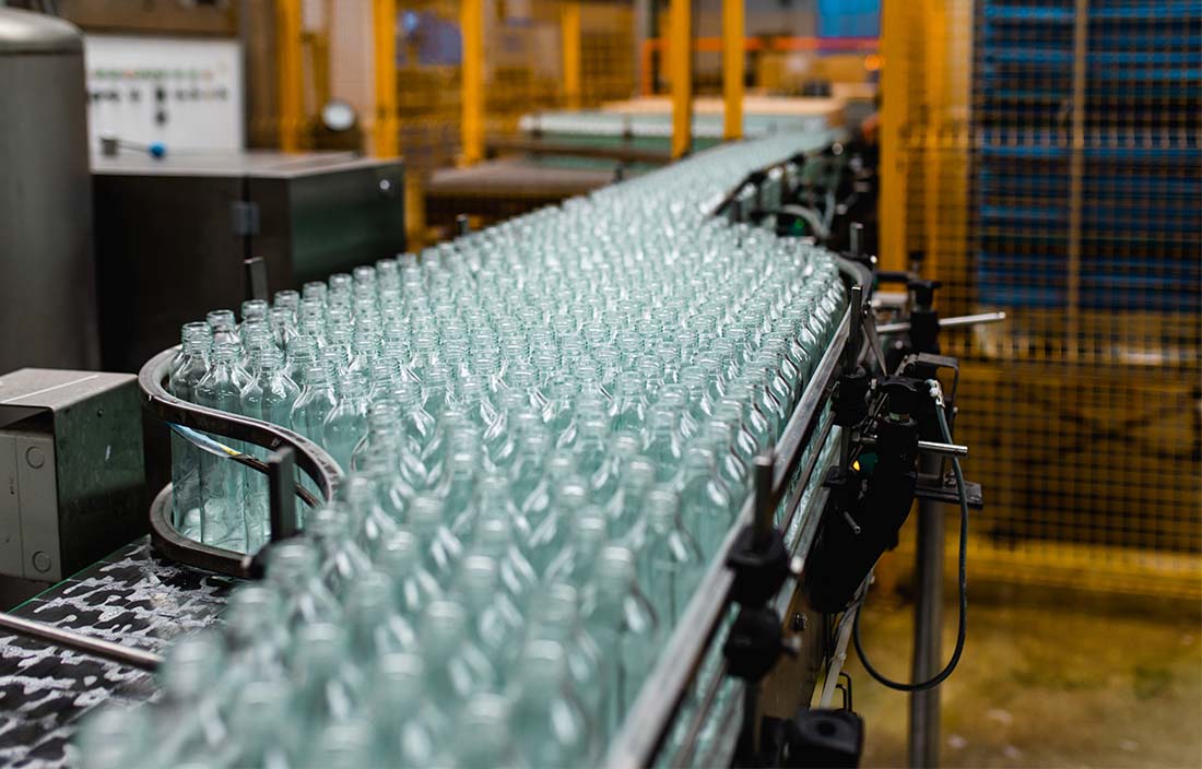 Close-up photo of glass bottles on a conveyor belt.