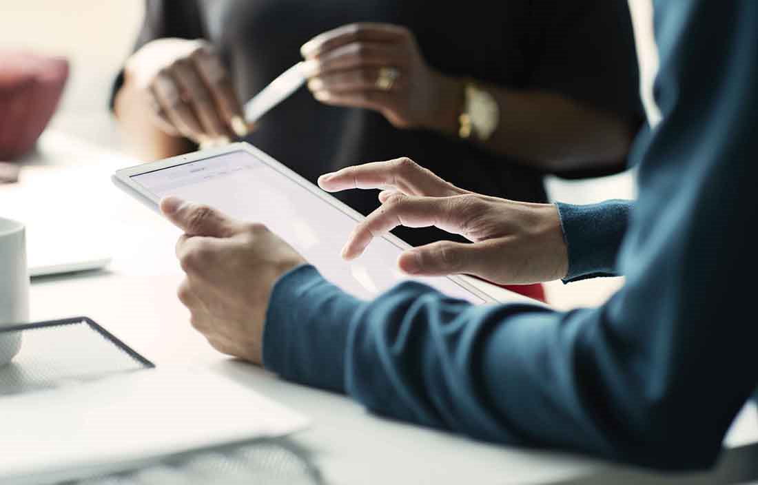 Close-up view of business professionals hands as they use tablet devices.