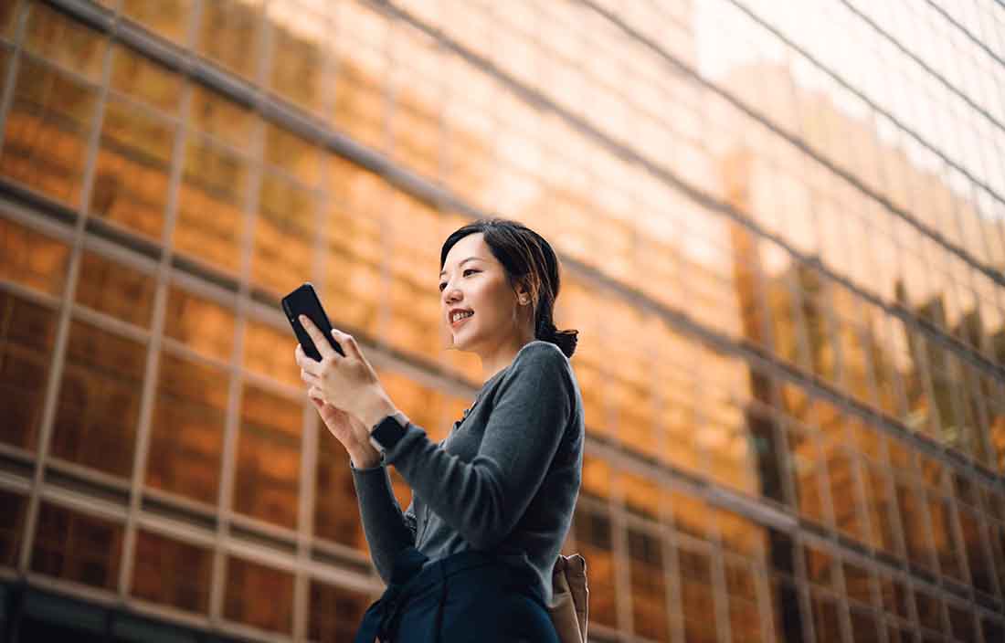 Business professional checking their phone outside of a building.