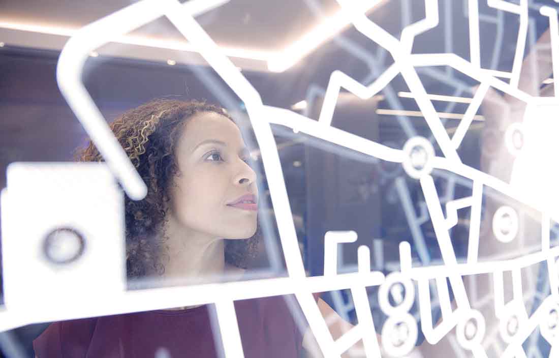 Business professional looking at a glass board with diagrams on it.