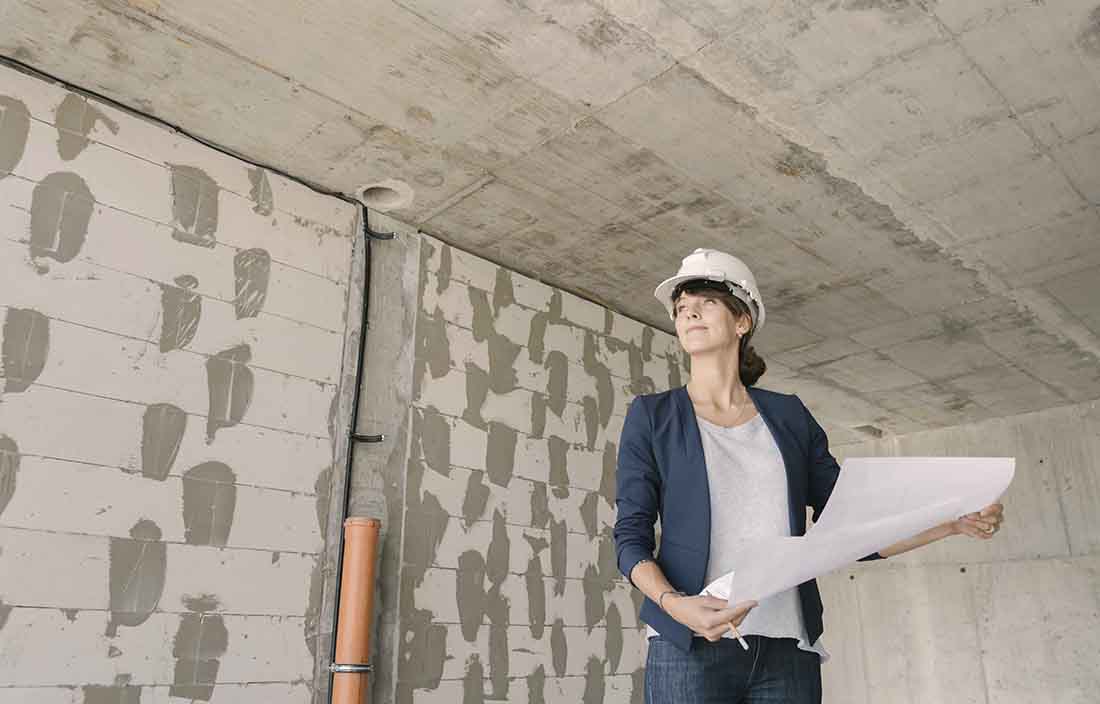 Construction leader wearing a hard hat and holding blueprint plans.