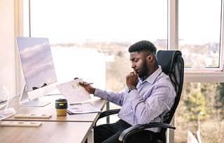 Business professional sitting at their desk reading paper documents.