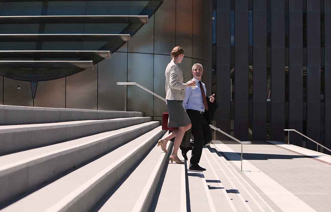 Two business professionals walking down a flight of stairs outside.