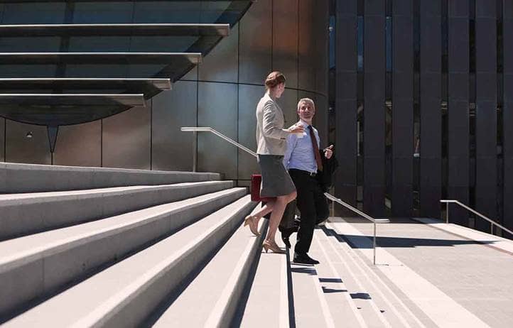 Two business owners walking down a column of stairs together.