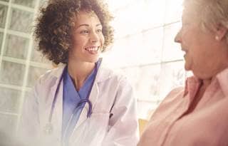 Doctor sitting and smiling while talking to an elderly patient.