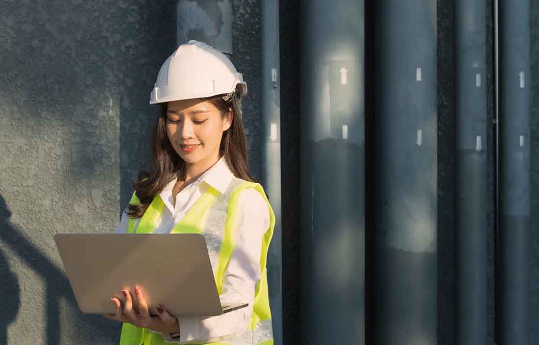 Manufacturing worker in a hard-hat using a laptop computer.