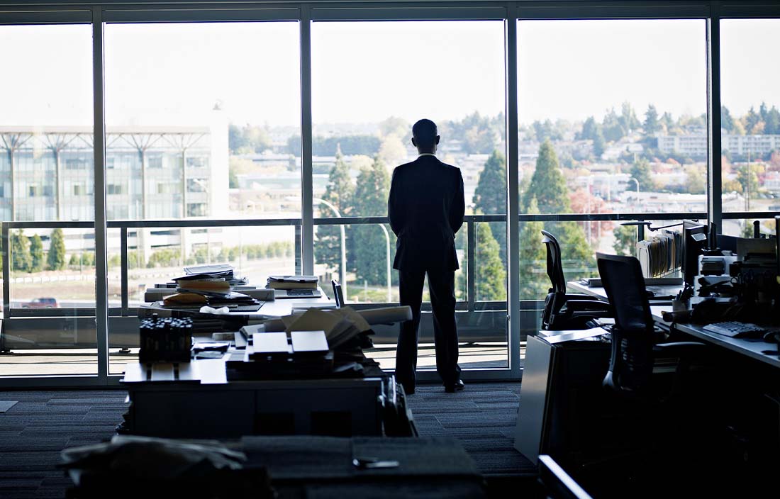 Business professional standing and looking out a window.