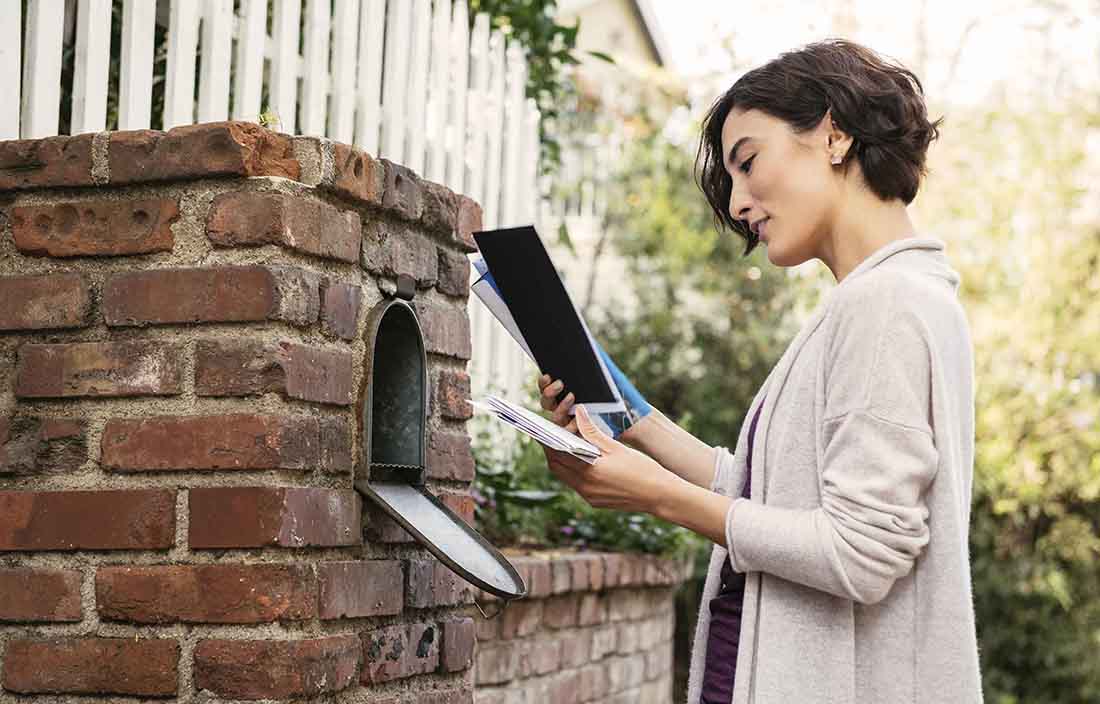 A woman checking mail from her mailbox.