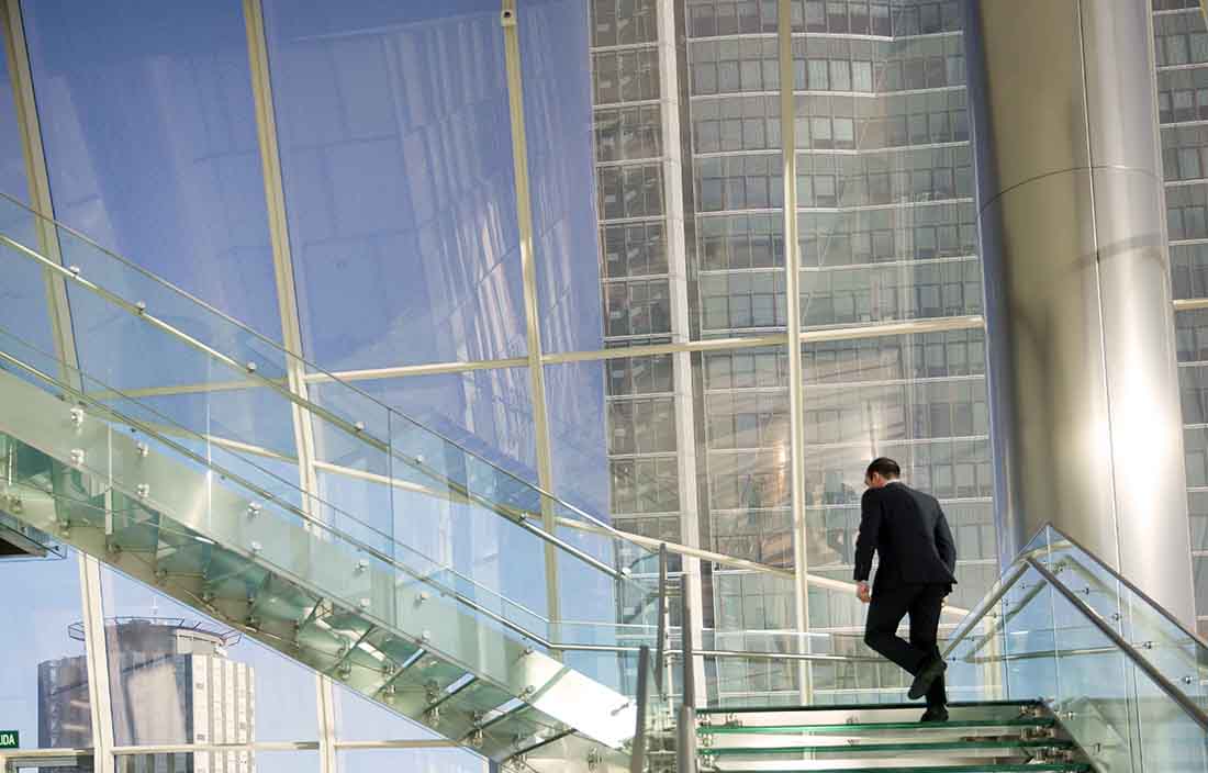 A business professional walking up a flight of stairs.