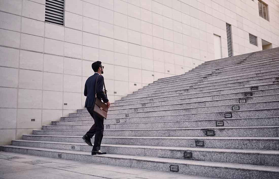 Business professional preparing to walk up a series of concrete steps.