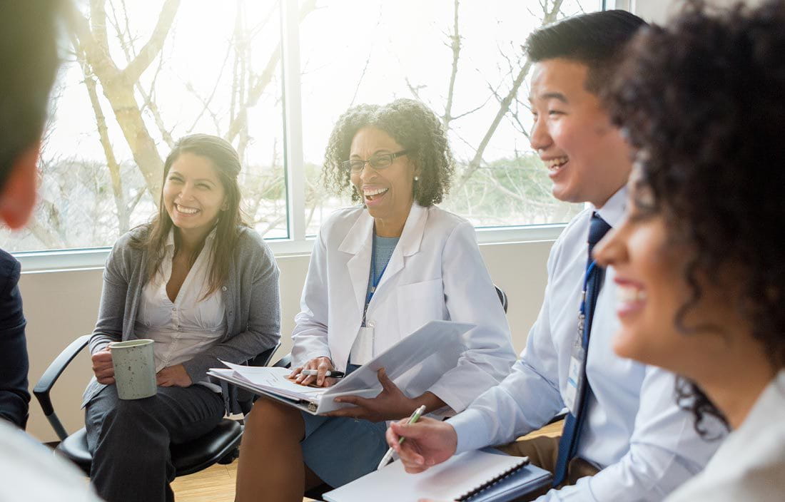 Doctors sitting together smiling in a room.