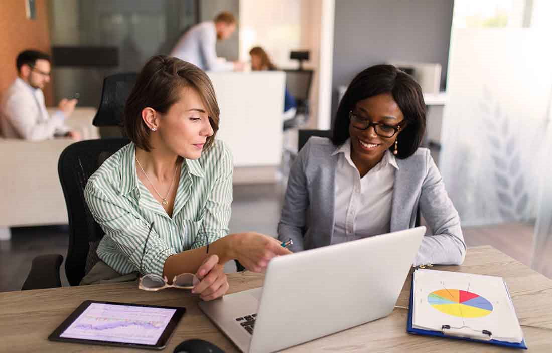 Two business professionals looking at information on a laptop computer screen.