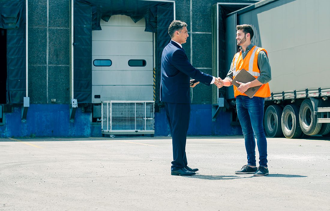 Business professional shaking hands with a shipping and receiving employee.