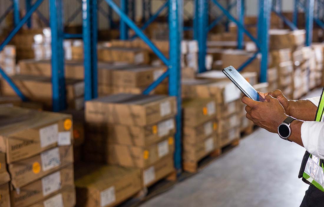 Close-up photo of hands holding a tablet device while in a warehouse.