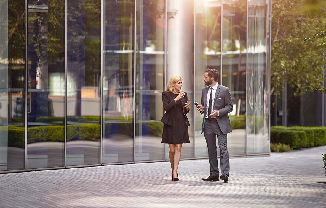 Two businesspeople talking outside of office building.