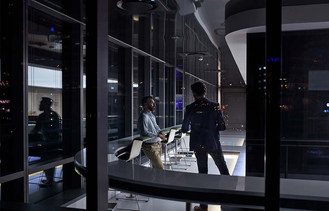 Two business professionals talking in office building at night.