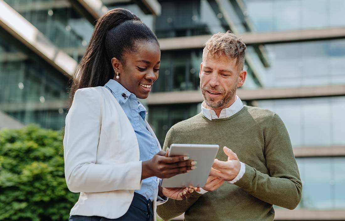 Two co-workers looking at information on a tablet together.
