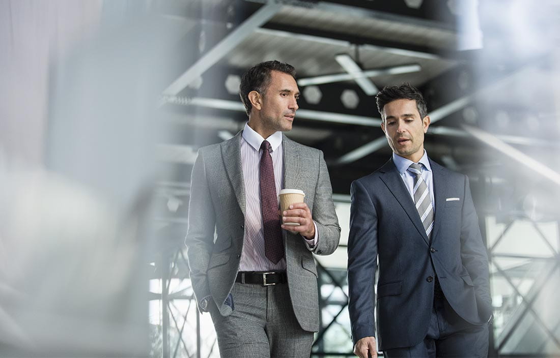 Two business professionals in suits walking together.