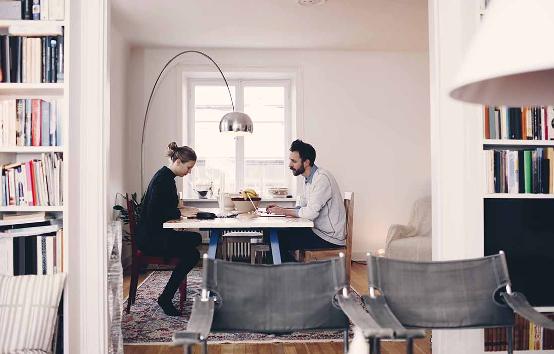 Two business professionals working from home at a kitchen table.