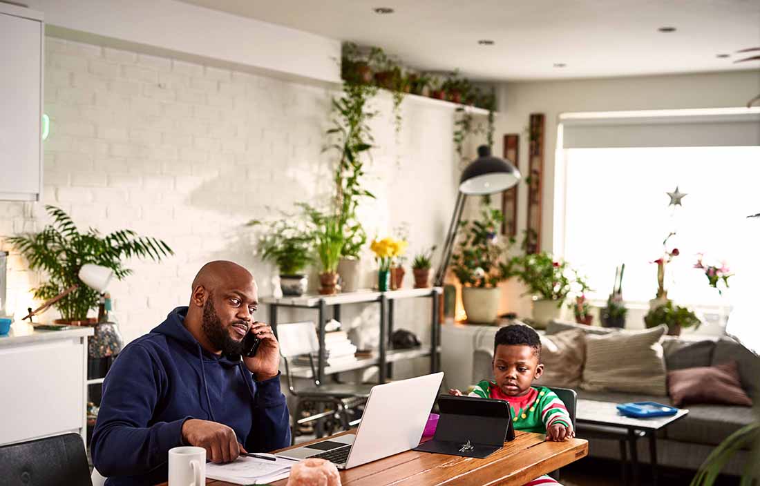 Parent sitting at a table with their son while recording finances.
