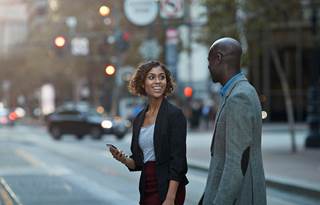 Two business professionals talking while walking across the street.