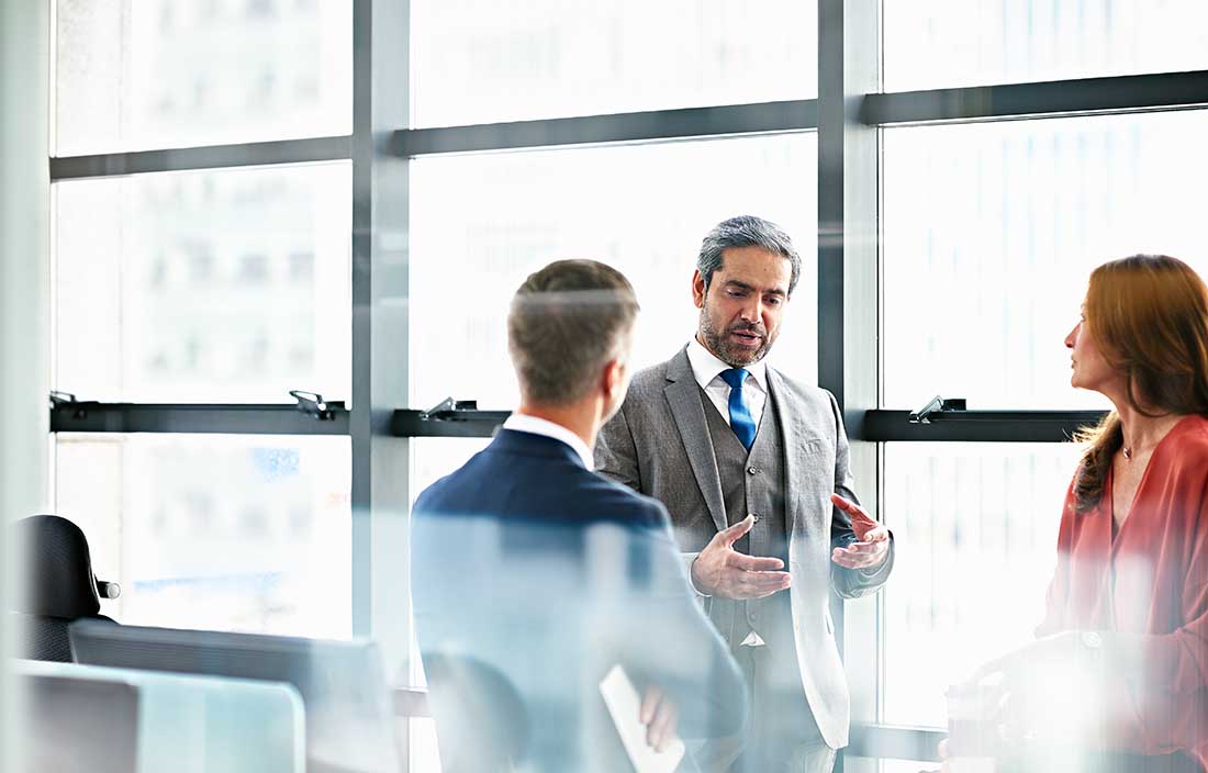 Three business professionals talking in a conference room.