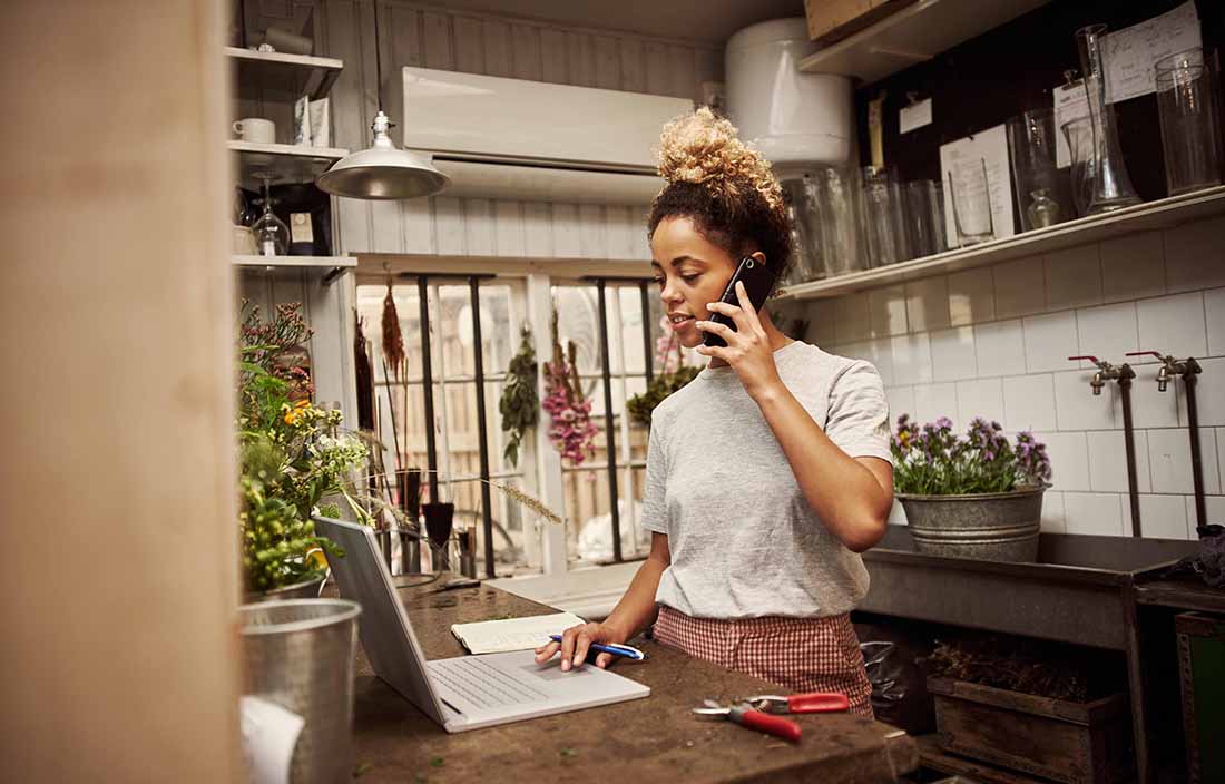 Person standing in their kitchen and talking on the phone.