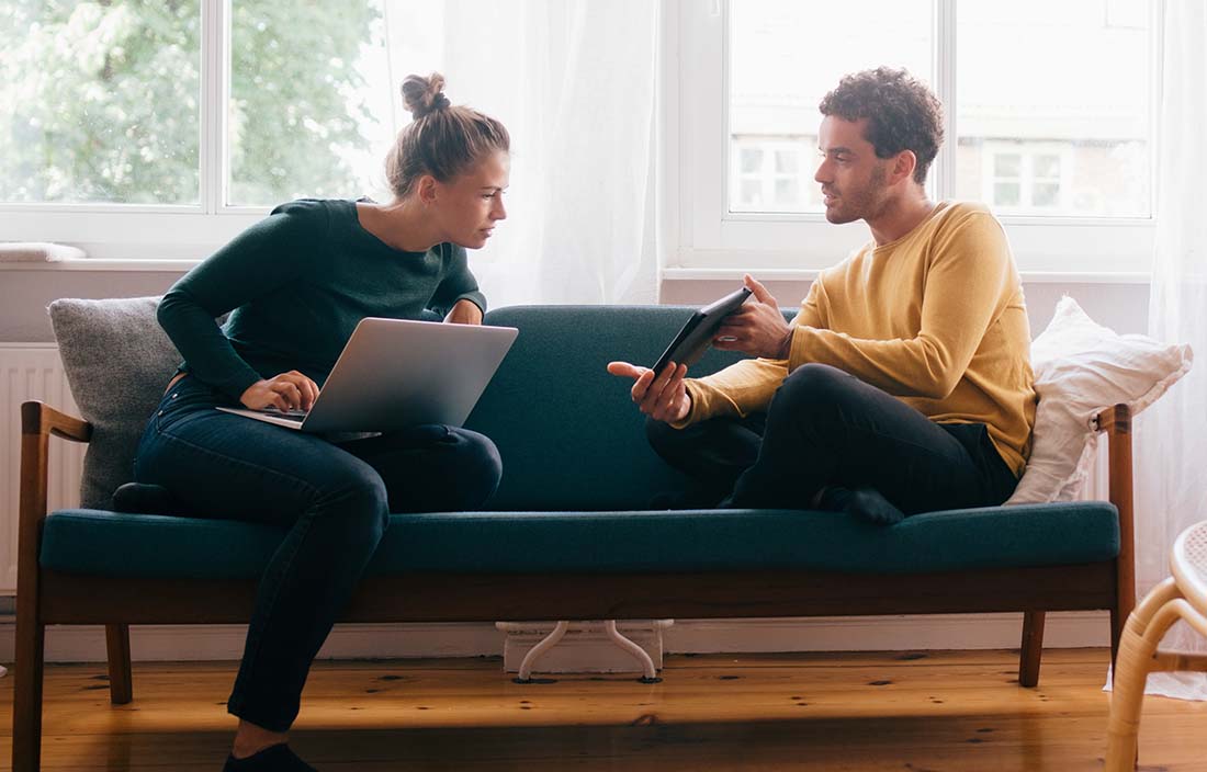 Couple sitting on couch and looking over finances.