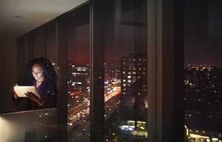 Business professional looking at tablet computer at nighttime.