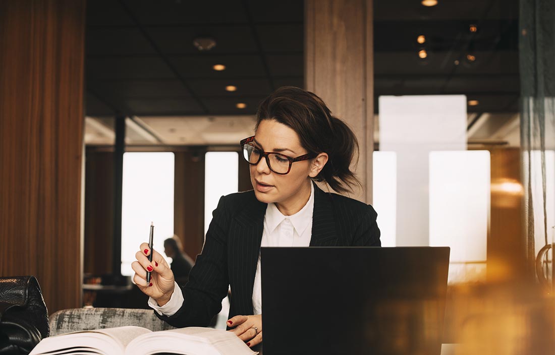 Business professional in a suit using a laptop computer on a desk.