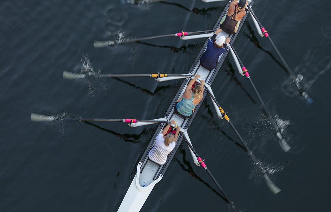 Top down view of a rowing team rowing through the water.