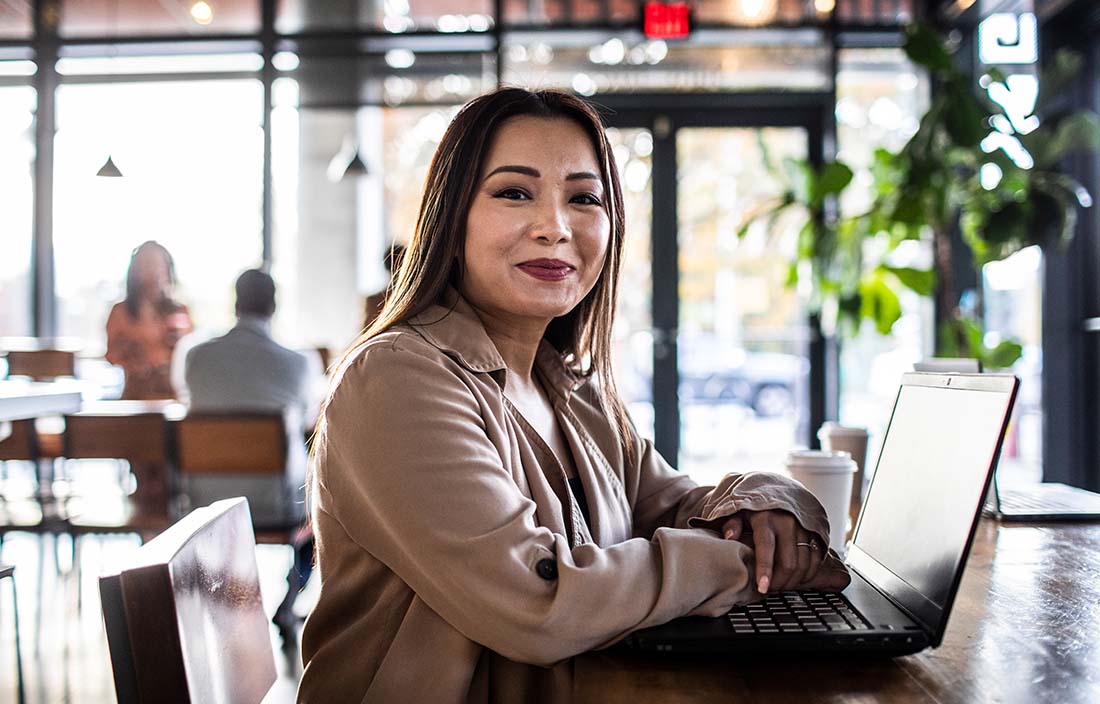 Young professional woman working in coffee shop using broadband internet access