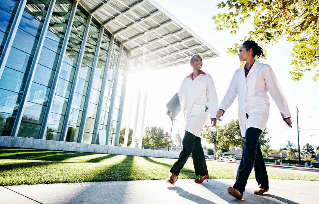 Two doctors walking outside a building.