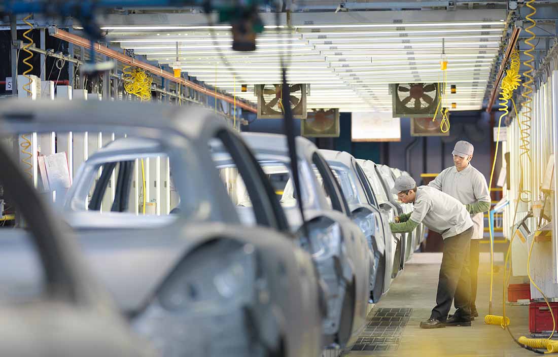 Automotive factory workers assembling vehicles at OEM production facility. 