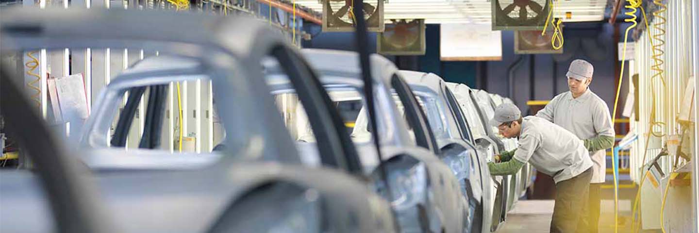 Automotive factory workers assembling vehicles at OEM production facility.