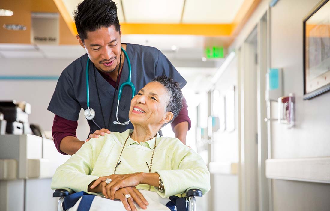Nurse pushing senior woman in wheelchair in a long-term living facility. 