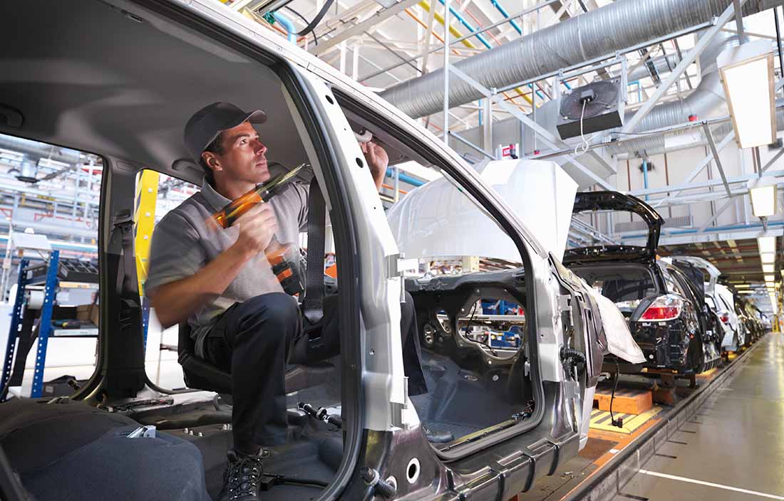 Automotive factory worker assembling an electrical vehicle.