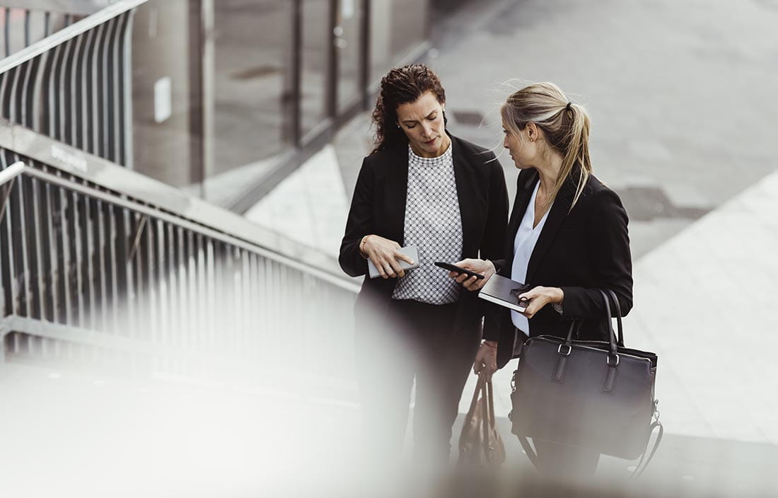 Two tax professionals looking at a mobile phone and walking up stairs.