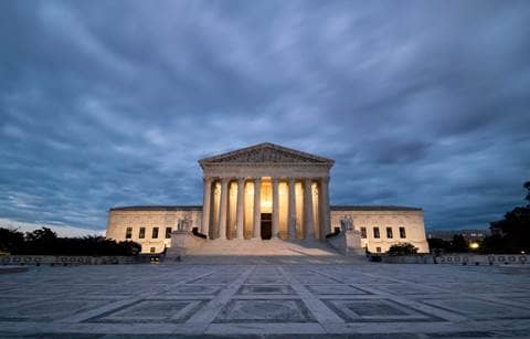 U.S. Supreme Court building lit up against a stormy night sky.
