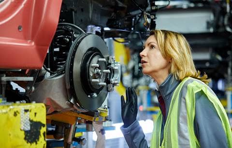 Auto worker checking the undercarriage of a car