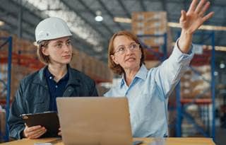 Manufacturers in a factory discussing data and analytics.