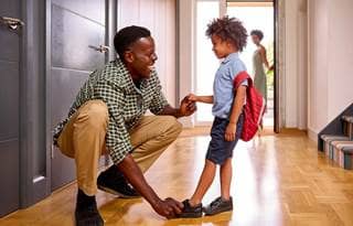 Parent smiling and helping their child get ready for school.