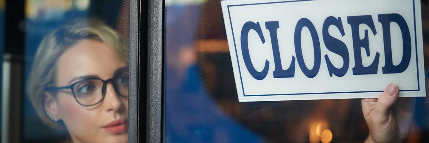 Business owner switching the sign on their door to "Closed".