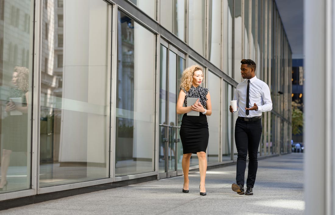 Two banking professionals walking and talking to each other.