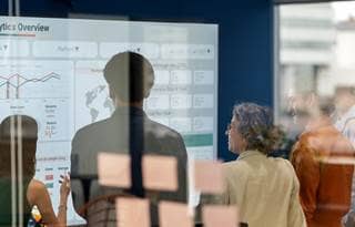 Business professionals looking at information projected on to a whiteboard