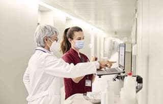 Healthcare professionals looking at their patient's charts in a hospital hallway.