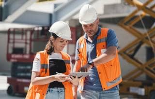 Building department professionals reviewing plans at a construction site, representing accreditation and continuous improvement.