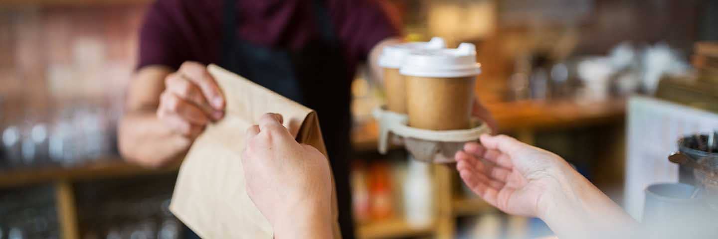 Barista handing a customer their coffee and pastry.